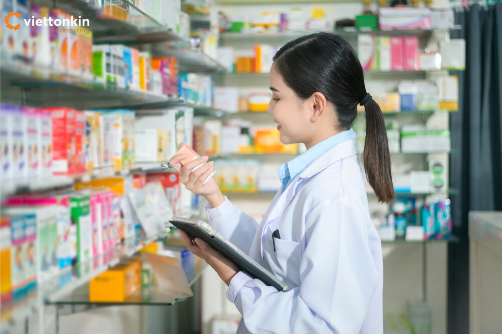 Nữ dược sĩ kiểm tra các sản phẩm thuốc trong một hiệu thuốc hiện đại, đại diện cho hoạt động kinh doanh dược phẩm và dịch vụ chăm sóc sức khỏe