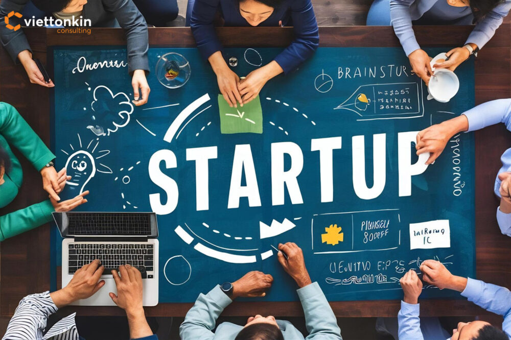 Nhóm doanh nhân thảo luận ý tưởng xung quanh một chiếc bàn lớn với từ ‘STARTUP’ ở trung tâm, tượng trưng cho môi trường khởi nghiệp đang trưởng thành của Việt Nam và văn hóa đổi mới hợp tác